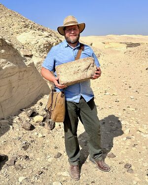 Nate Loper holding a mud brick at the Pyramid of Senusret II in Egypt